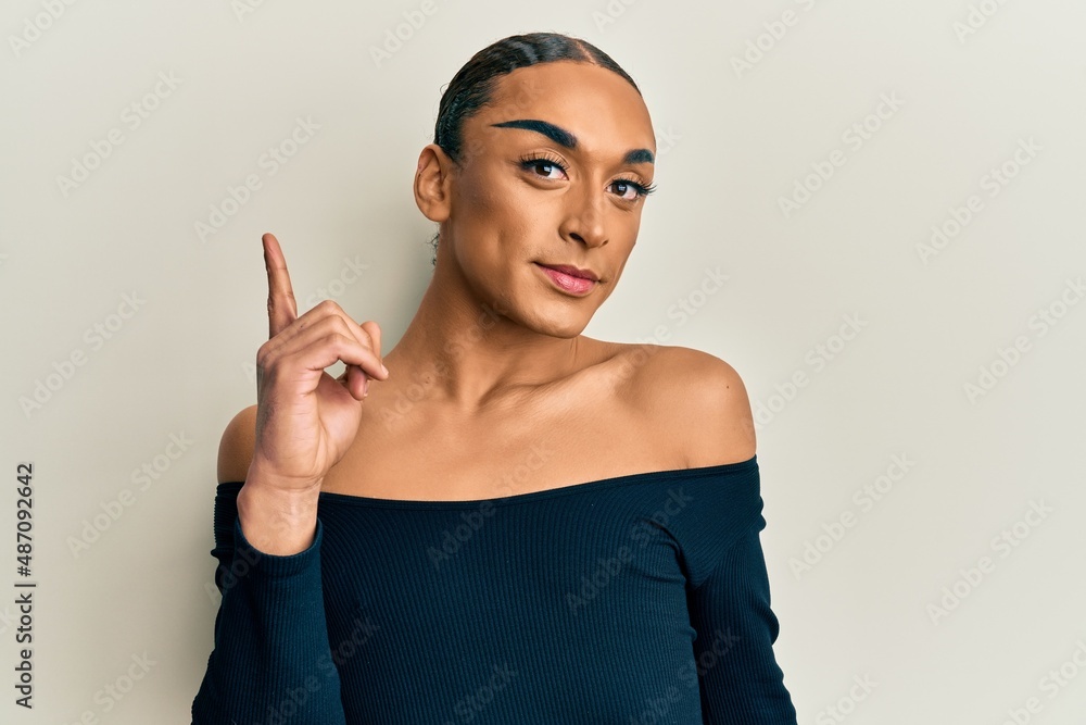 Hispanic man wearing make up and long hair wearing woman fashion clothes smiling with an idea or question pointing finger up with happy face, number one Hispanic man wearing make up and long hair wearing woman fashion clothes smiling with an idea or question pointing finger up with happy face, number one