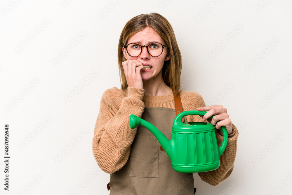 Young gardener woman holding a sprinkler isolated on white background biting fingernails, nervous and very anxious. Young gardener woman holding a sprinkler isolated on white background biting fingernails, nervous and very anxious.