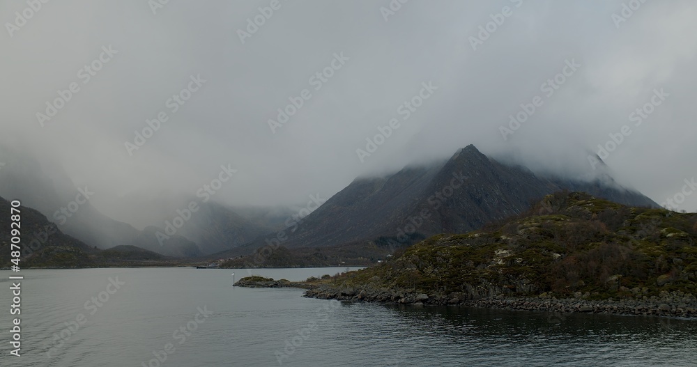 Fototapeta premium A landscape view of a ferry at sea, with the harbour in the distance, on the Lofoten islands.