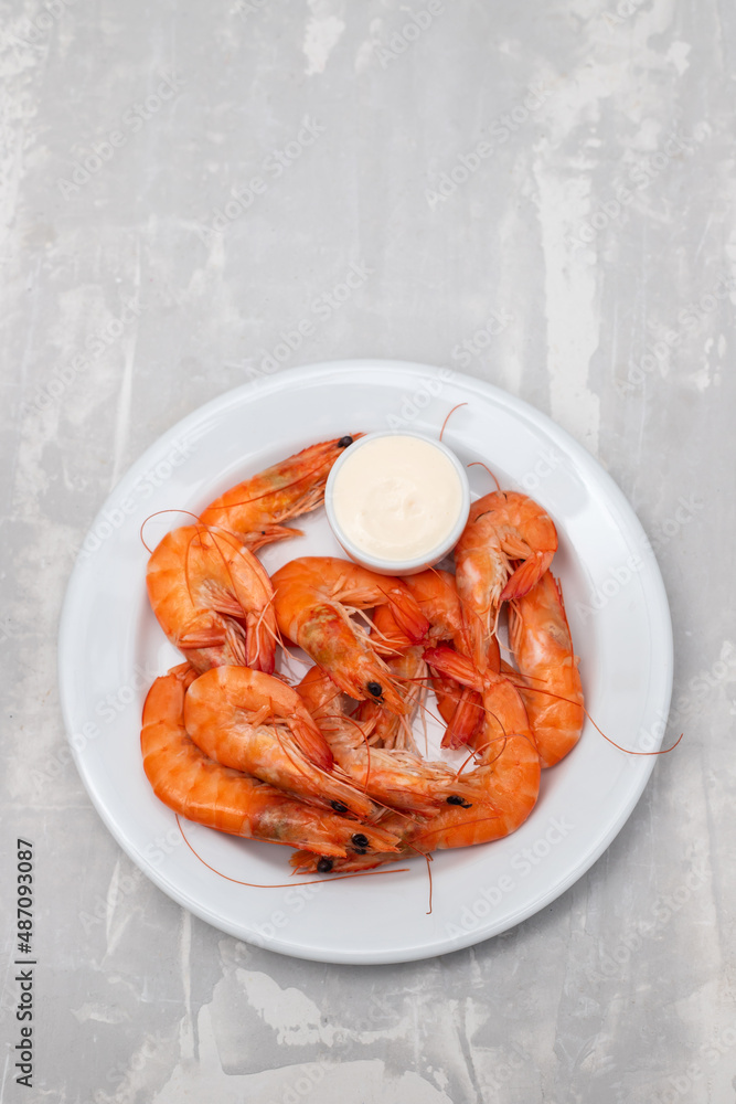 Boiled fresh shrimps with sauce in small bowl on white plate on ceramic Boiled fresh shrimps with sauce in small bowl on white plate on ceramic