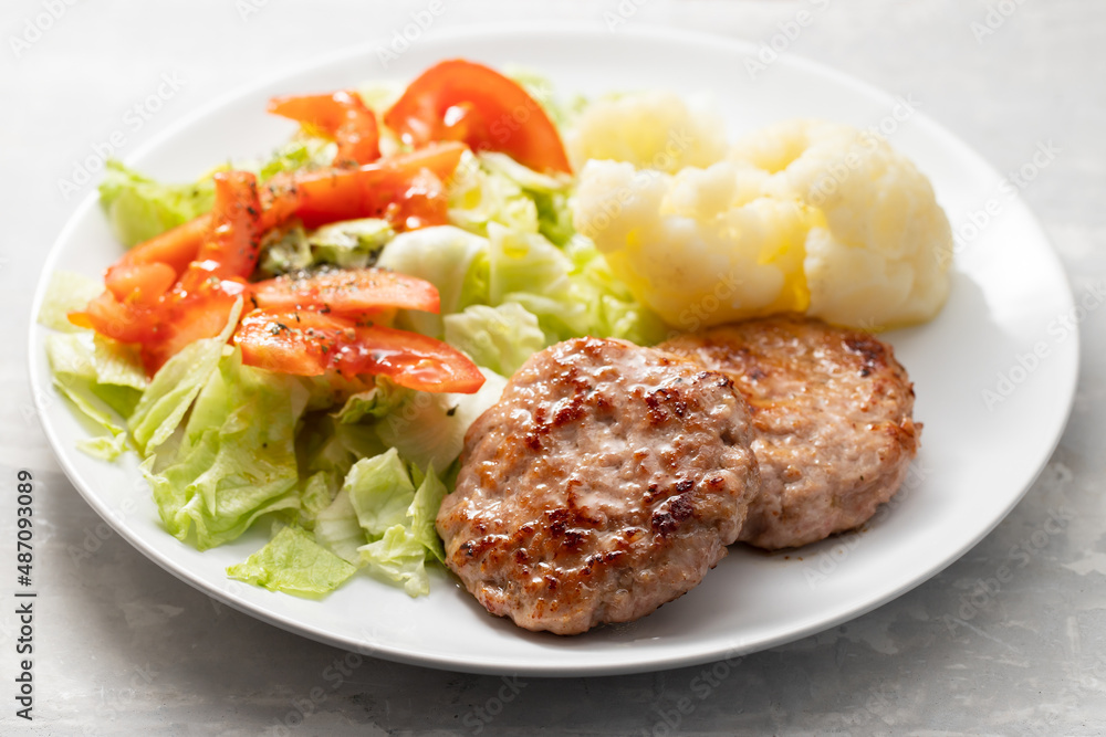 Fried ground meat with fresh salad and boiled cauliflower on white plate Fried ground meat with fresh salad and boiled cauliflower on white plate