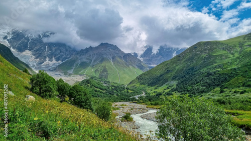 Fototapeta Naklejka Na Ścianę i Meble -  Patara Enguri River flowing down the a valley with view on the Shkhara Glacier in the Greater Caucasus Mountain Range in Georgia, Svaneti Region, Ushguli. Snow-capped mountains in the back. Wilderness