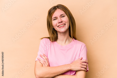 Young English woman isolated on beige background who feels confident, crossing arms with determination.