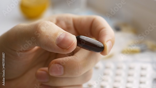 Close-up of a brown medicine capsule held in fingers  a pill prescribed by a doctor for the treatment of an infectious disease. Coronavirus treatment. Vitamins.