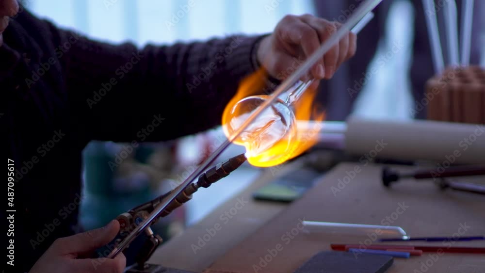 Experienced glass blower working with flame on a handmade art piece of glass Experienced glass blower working with flame on a handmade art piece of glass