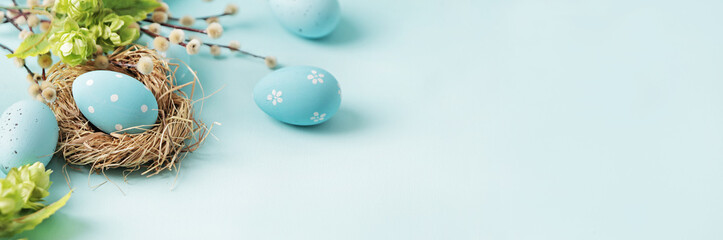 pastel blue easter eggs in bird nest on blue background. copy space for text