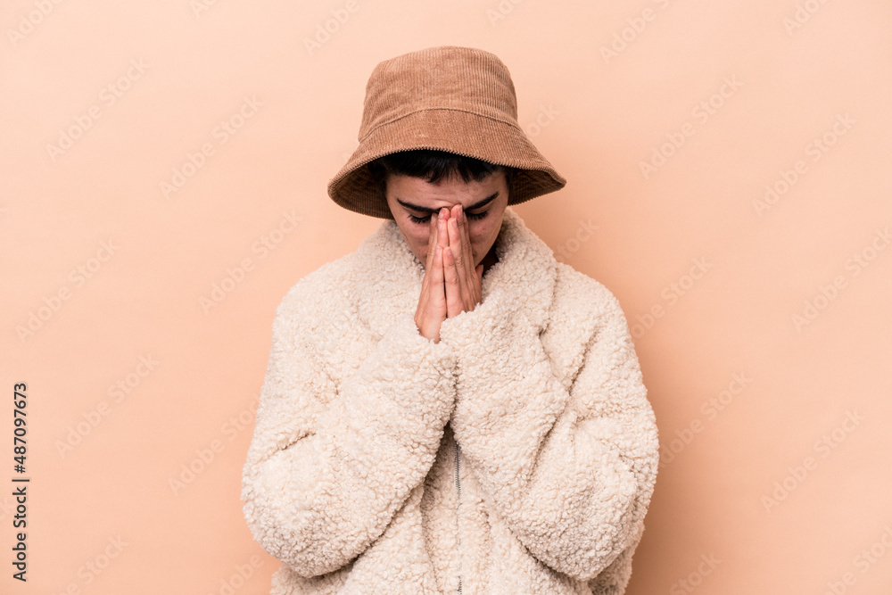 Young caucasian woman isolated on beige background praying, showing devotion, religious person looking for divine inspiration. Young caucasian woman isolated on beige background praying, showing devotion, religious person looking for divine inspiration.