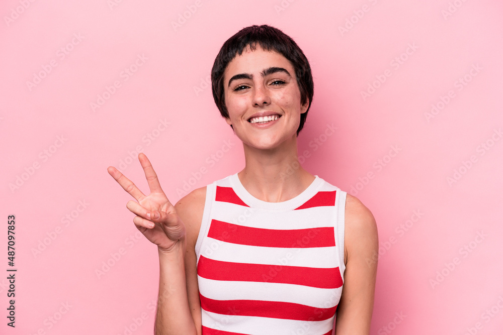 Young caucasian woman isolated on pink background showing victory sign and smiling broadly. Young caucasian woman isolated on pink background showing victory sign and smiling broadly.