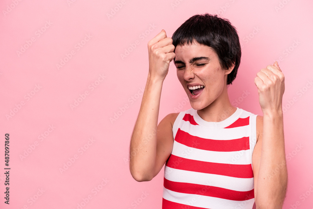 Young caucasian woman isolated on pink background raising fist after a victory, winner concept. Young caucasian woman isolated on pink background raising fist after a victory, winner concept.