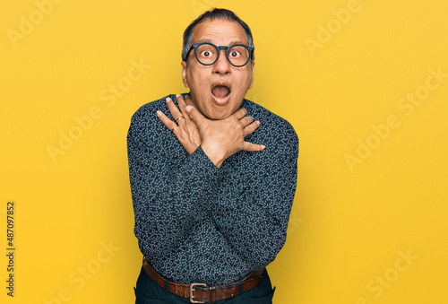 Middle age indian man wearing casual clothes and glasses shouting and suffocate because painful strangle. health problem. asphyxiate and suicide concept.