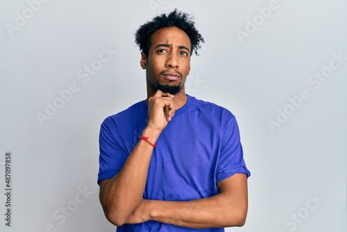 Young african american man with beard wearing casual blue t shirt thinking concentrated about doubt with finger on chin and looking up wondering © Krakenimages.com