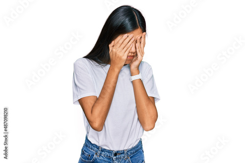Beautiful young asian woman wearing casual white t shirt with sad expression covering face with hands while crying. depression concept.