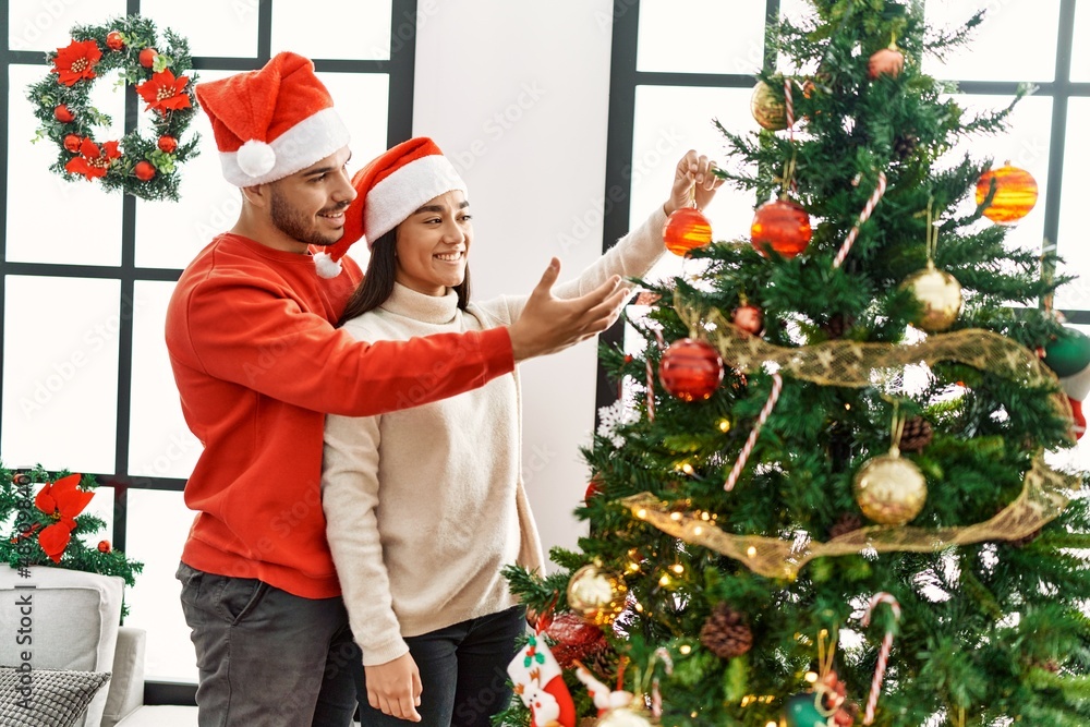 Young hispanic couple smiling happy decorating christmas tree at home. Young hispanic couple smiling happy decorating christmas tree at home.