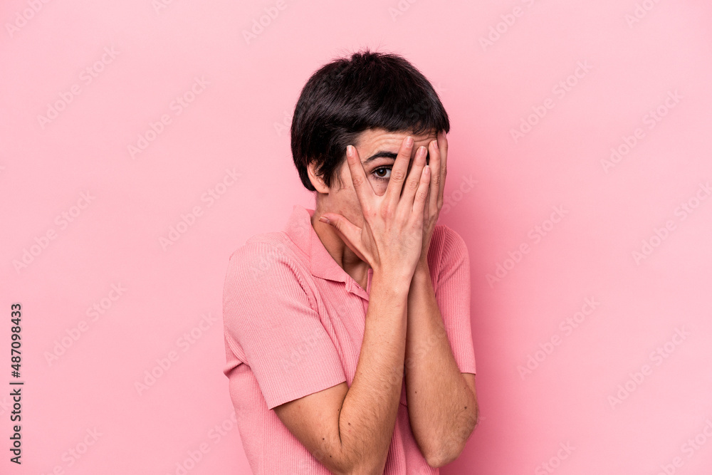 Young caucasian woman isolated on pink background blink through fingers frightened and nervous. Young caucasian woman isolated on pink background blink through fingers frightened and nervous.