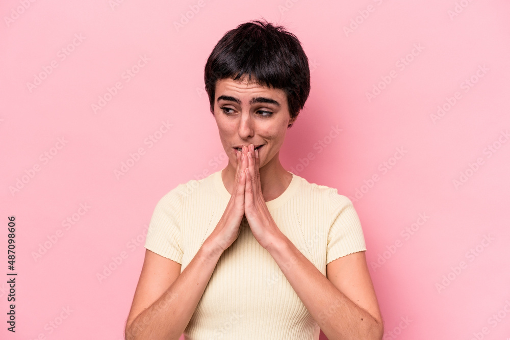 Young caucasian woman isolated on pink background praying, showing devotion, religious person looking for divine inspiration. Young caucasian woman isolated on pink background praying, showing devotion, religious person looking for divine inspiration.