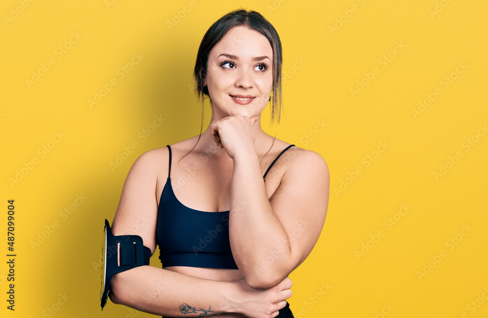 Young hispanic woman wearing sportswear with hand on chin thinking about question, pensive expression. smiling with thoughtful face. doubt concept. Young hispanic woman wearing sportswear with hand on chin thinking about question, pensive expression. smiling with thoughtful face. doubt concept.