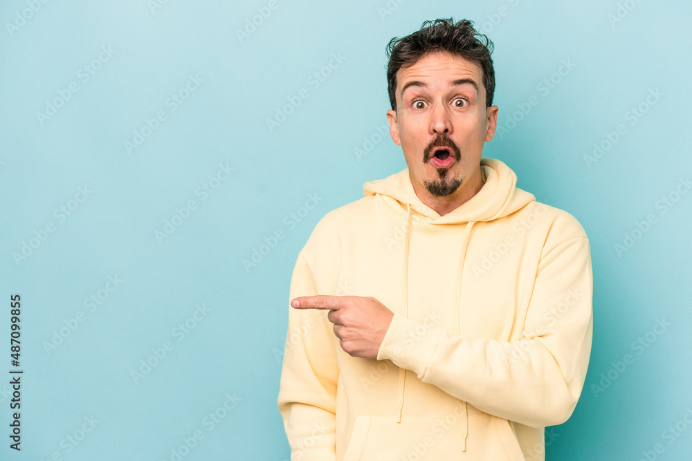 Young caucasian man isolated on blue background pointing to the side Young caucasian man isolated on blue background pointing to the side