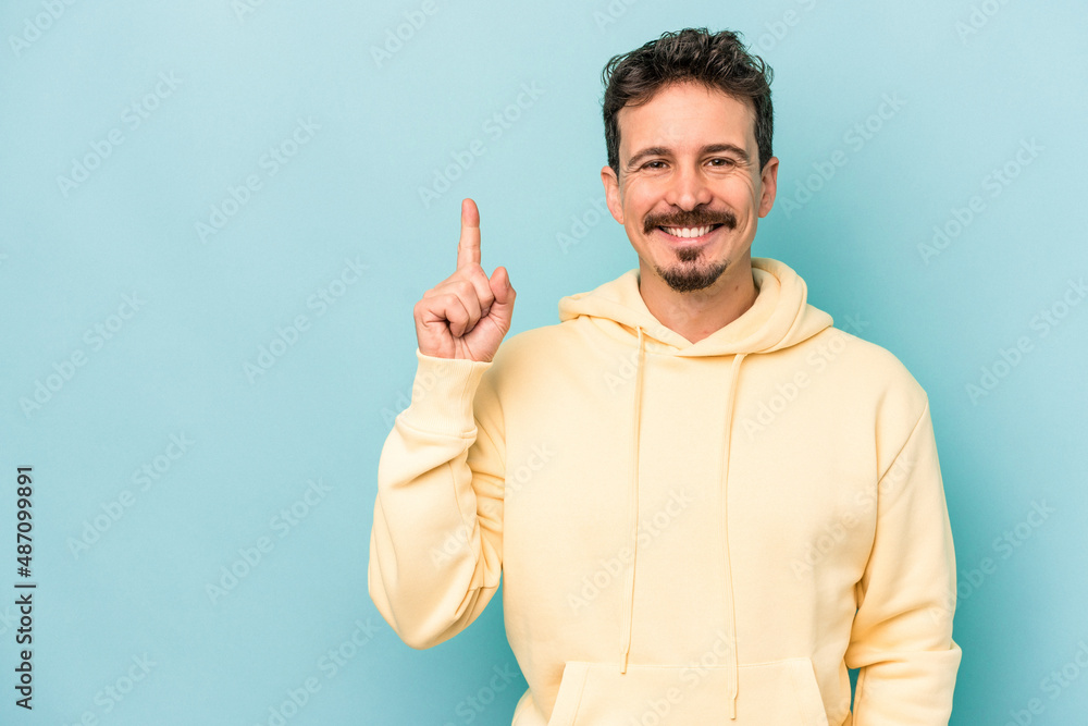 Young caucasian man isolated on blue background showing number one with finger. Young caucasian man isolated on blue background showing number one with finger.