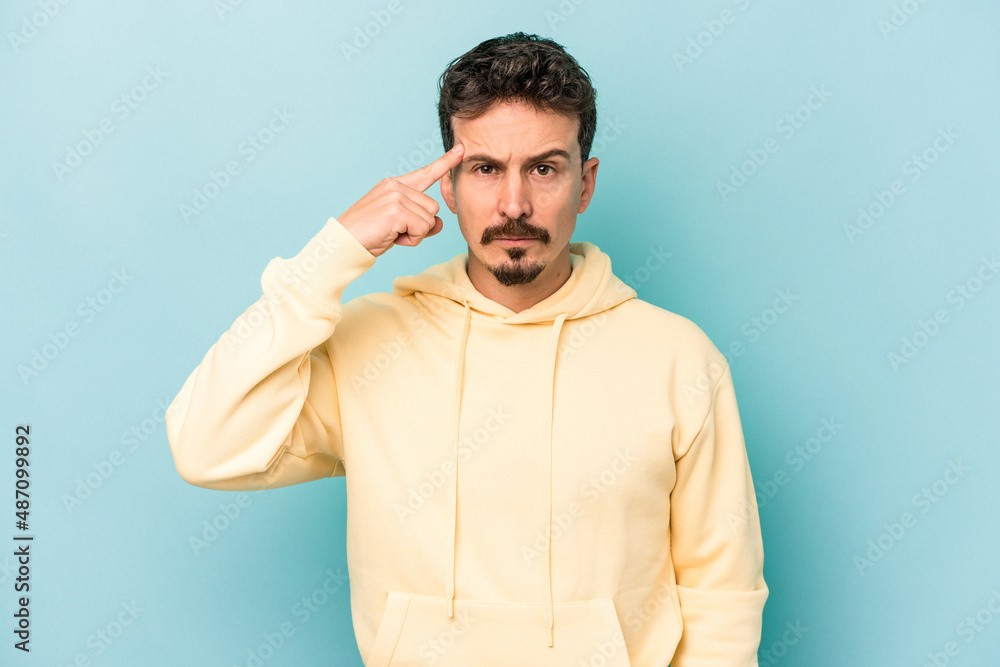Young caucasian man isolated on blue background pointing temple with finger, thinking, focused on a task. Young caucasian man isolated on blue background pointing temple with finger, thinking, focused on a task.
