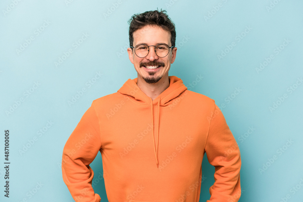 Young caucasian man isolated on blue background confident keeping hands on hips. Young caucasian man isolated on blue background confident keeping hands on hips.