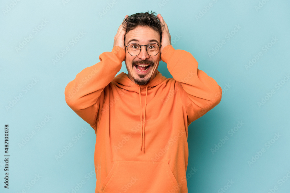 Young caucasian man isolated on blue background screaming, very excited, passionate, satisfied with something. Young caucasian man isolated on blue background screaming, very excited, passionate, satisfied with something.