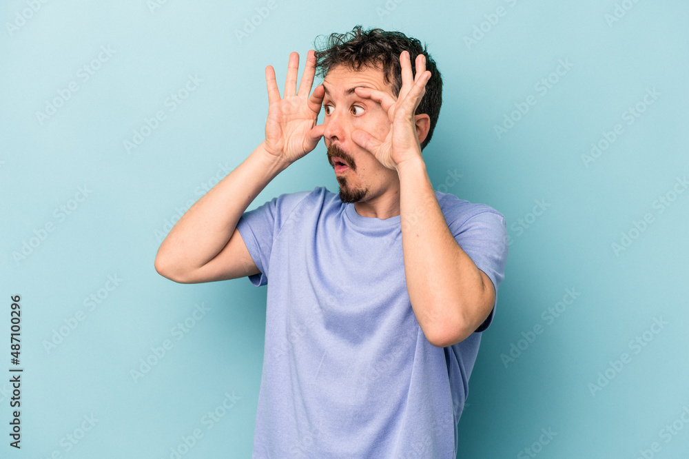 Young caucasian man isolated on blue background keeping eyes opened to find a success opportunity. Young caucasian man isolated on blue background keeping eyes opened to find a success opportunity.