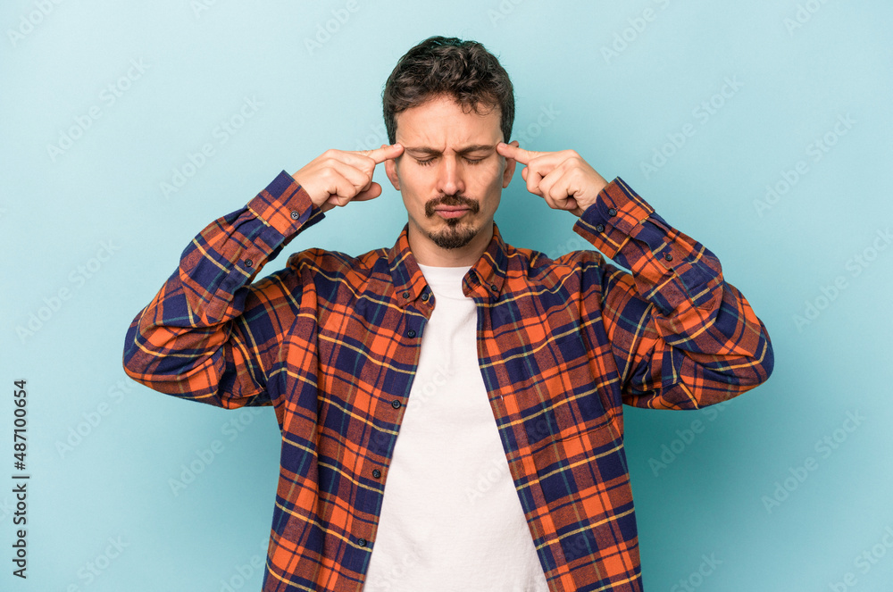 Young caucasian man isolated on blue background focused on a task, keeping forefingers pointing head. Young caucasian man isolated on blue background focused on a task, keeping forefingers pointing head.