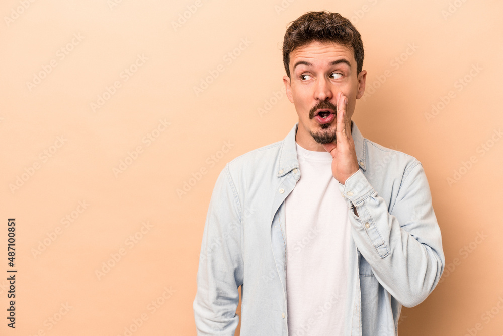 Young caucasian man isolated on beige background is saying a secret hot braking news and looking aside Young caucasian man isolated on beige background is saying a secret hot braking news and looking aside