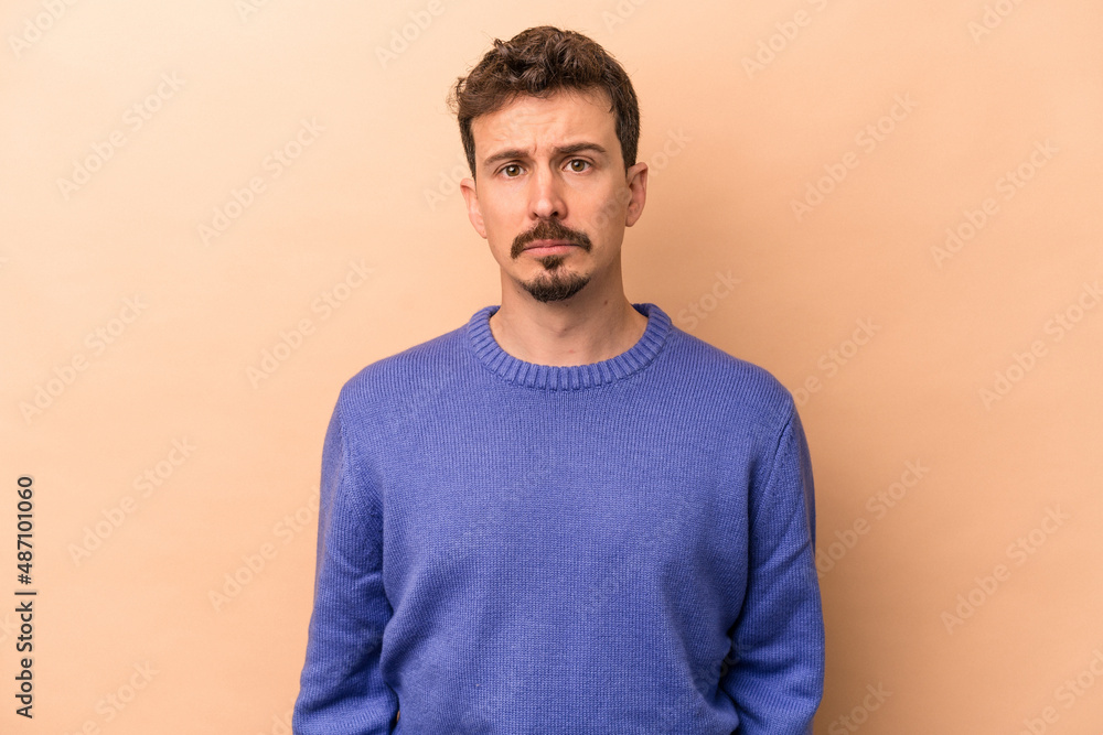 Young caucasian man isolated on beige background sad, serious face, feeling miserable and displeased. Young caucasian man isolated on beige background sad, serious face, feeling miserable and displeased.