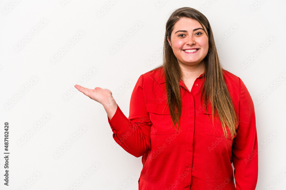 Young caucasian overweight woman isolated on white background showing a copy space on a palm and holding another hand on waist. Young caucasian overweight woman isolated on white background showing a copy space on a palm and holding another hand on waist.