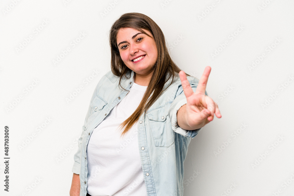 Young caucasian overweight woman isolated on white background joyful and carefree showing a peace symbol with fingers. Young caucasian overweight woman isolated on white background joyful and carefree showing a peace symbol with fingers.