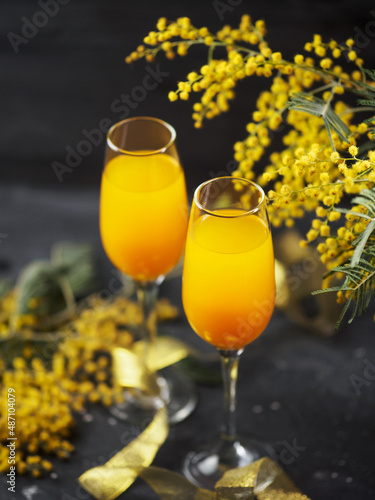 two glasses of mimosa cocktail and a bouquet of yellow mimosas