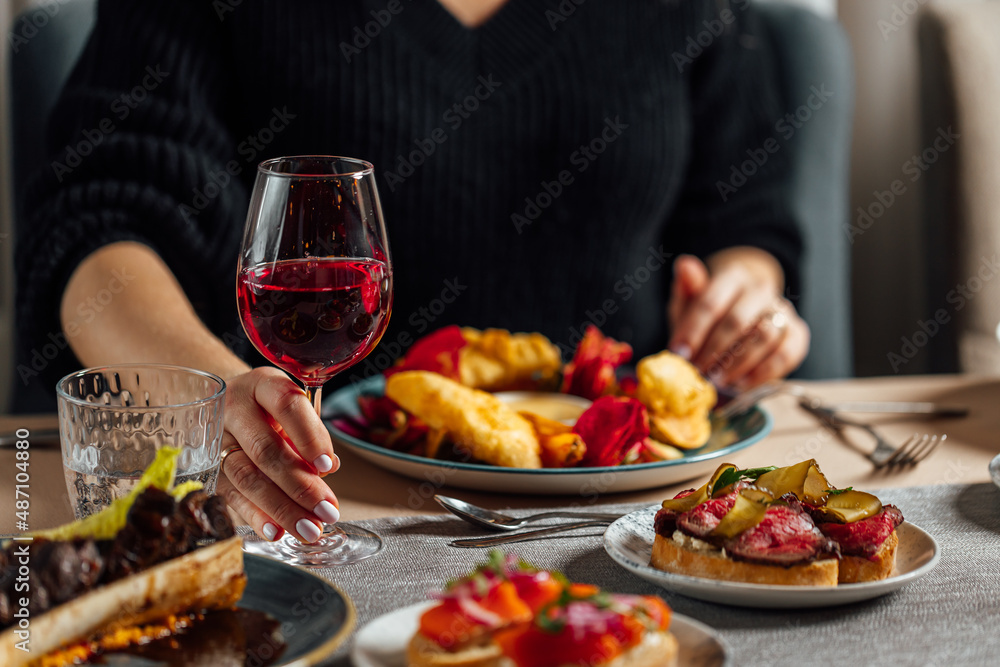 Women having dinner at the restaurant, Holding glass of red wine in hands.