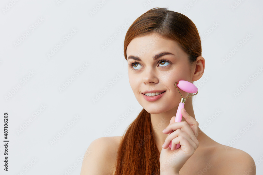young woman pink quartz roller scraper skin care massage bare shoulders isolated background young woman pink quartz roller scraper skin care massage bare shoulders isolated background