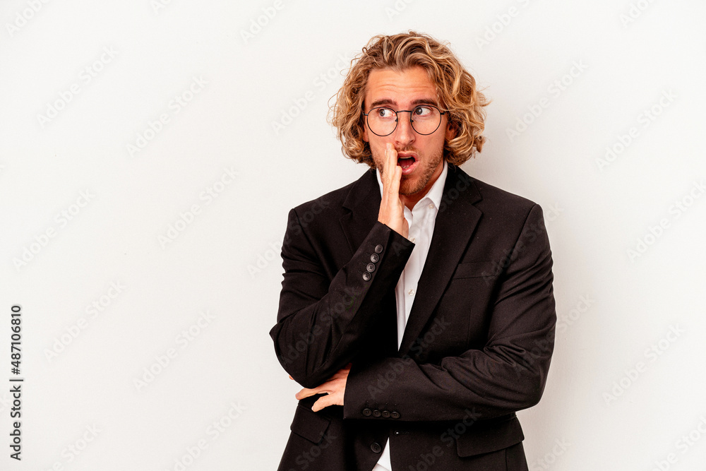 Young caucasian business man isolated on white background is saying a secret hot braking news and looking aside