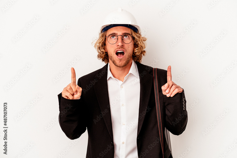 Young architect caucasian man with helmet isolated on white background pointing upside with opened mouth. Young architect caucasian man with helmet isolated on white background pointing upside with opened mouth.