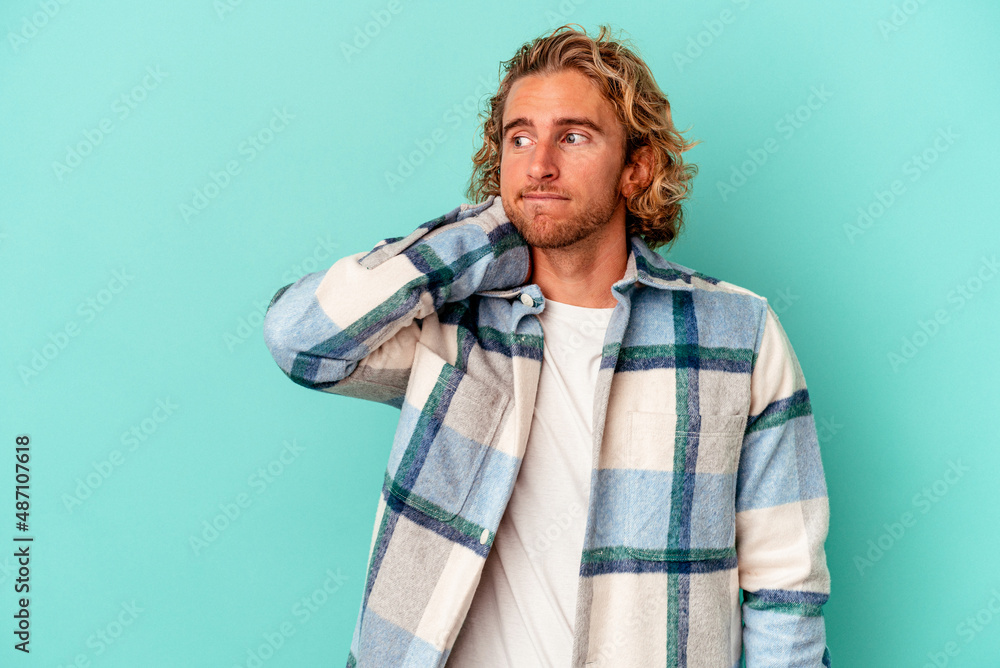 Young caucasian man isolated on blue background touching back of head, thinking and making a choice. Young caucasian man isolated on blue background touching back of head, thinking and making a choice.