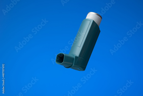 Asthma inhaler, generic, non-branded. Close up studio shot, isolated on blue background