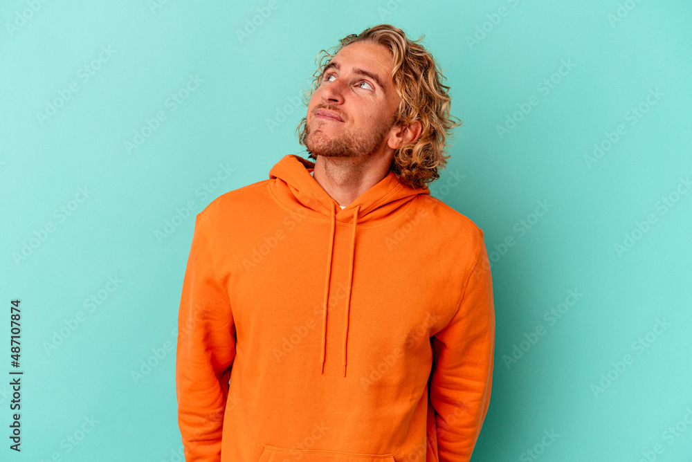 Young caucasian man isolated on blue background relaxed and happy laughing, neck stretched showing teeth. Young caucasian man isolated on blue background relaxed and happy laughing, neck stretched showing teeth.