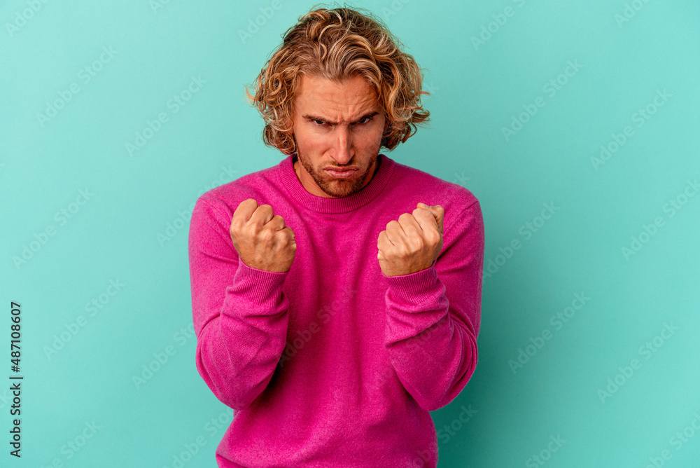 Young caucasian man isolated on blue background upset screaming with tense hands. Young caucasian man isolated on blue background upset screaming with tense hands.