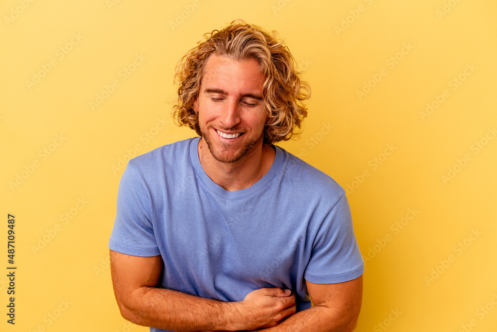 Young caucasian man isolated on yellow background laughing and having fun. Young caucasian man isolated on yellow background laughing and having fun.