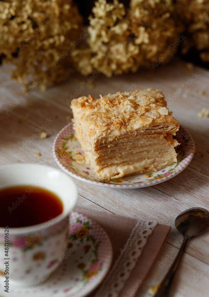 cake lies on a plate next to a cup of tea and a spoon cake lies on a plate next to a cup of tea and a spoon