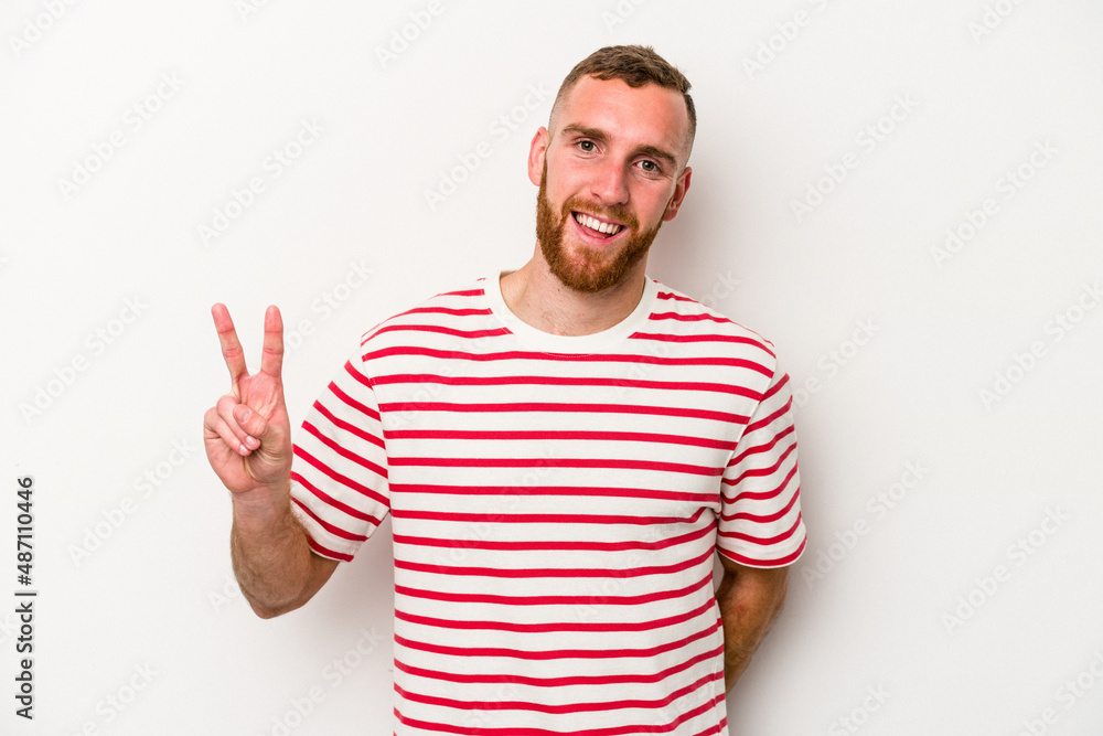 Naklejka premium Young caucasian man isolated on white background showing victory sign and smiling broadly.