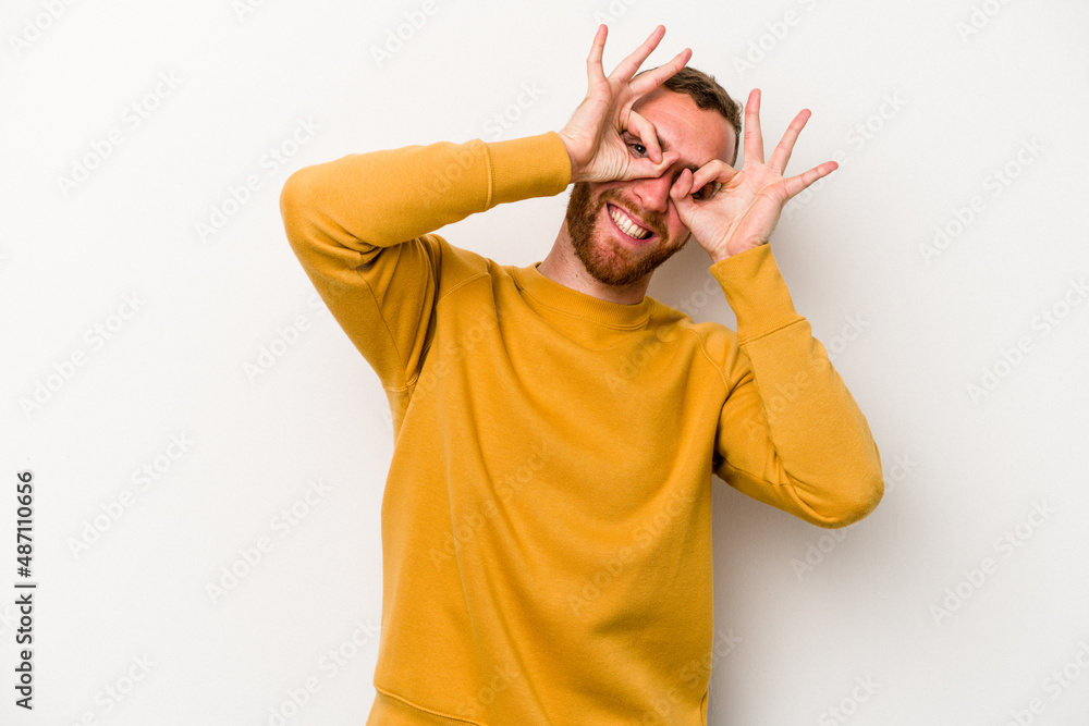 Young caucasian man isolated on white background showing okay sign over eyes Young caucasian man isolated on white background showing okay sign over eyes