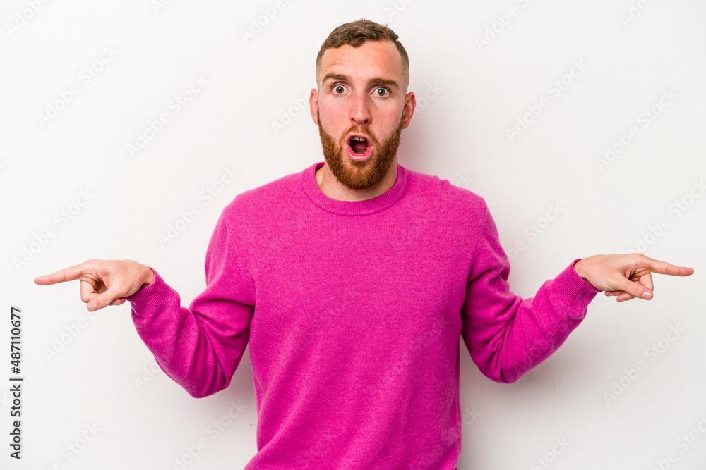 Young caucasian man isolated on white background pointing to different copy spaces, choosing one of them, showing with finger. Young caucasian man isolated on white background pointing to different copy spaces, choosing one of them, showing with finger.