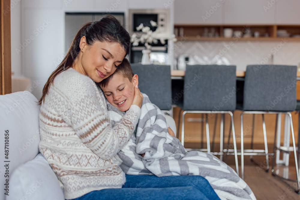 Peaceful little caucasian boy, resting on his mother's shoulder, wraped in a blanket. Peaceful little caucasian boy, resting on his mother's shoulder, wraped in a blanket.