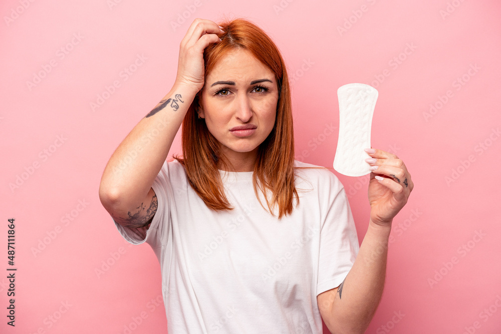 Young caucasian woman holding sanitary napkin isolated on pink background being shocked, she has remembered important meeting. Young caucasian woman holding sanitary napkin isolated on pink background being shocked, she has remembered important meeting.