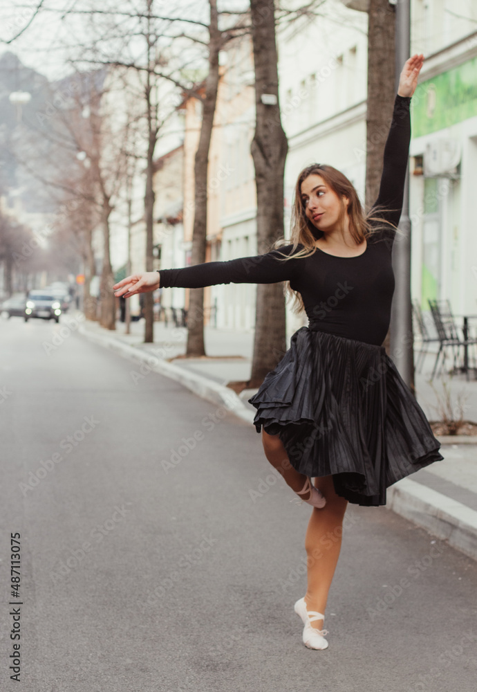 A woman crossing the street in a dancing outfit, in a dance pose. A woman crossing the street in a dancing outfit, in a dance pose.