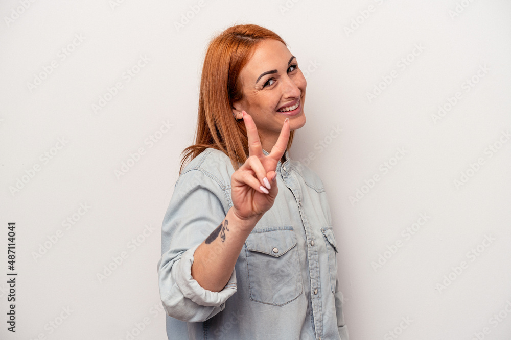 Young caucasian woman isolated on white background joyful and carefree showing a peace symbol with fingers. Young caucasian woman isolated on white background joyful and carefree showing a peace symbol with fingers.