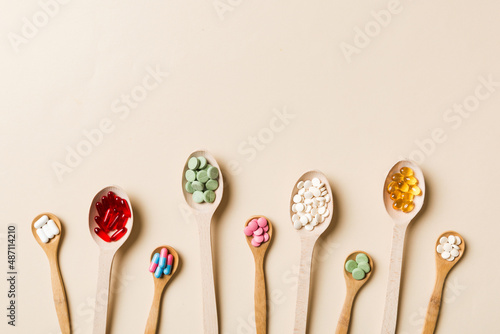 Schilderij op canvas Top view Variety of vitamin and mineral pills in wooden spoon on Colored background